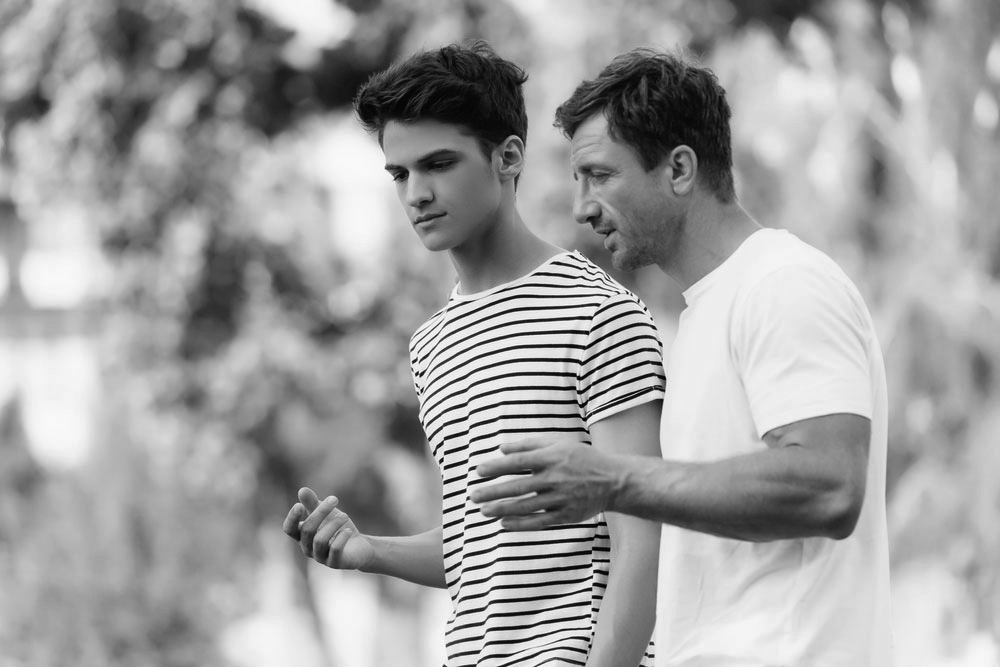 father and teenage son having a conversation while walking