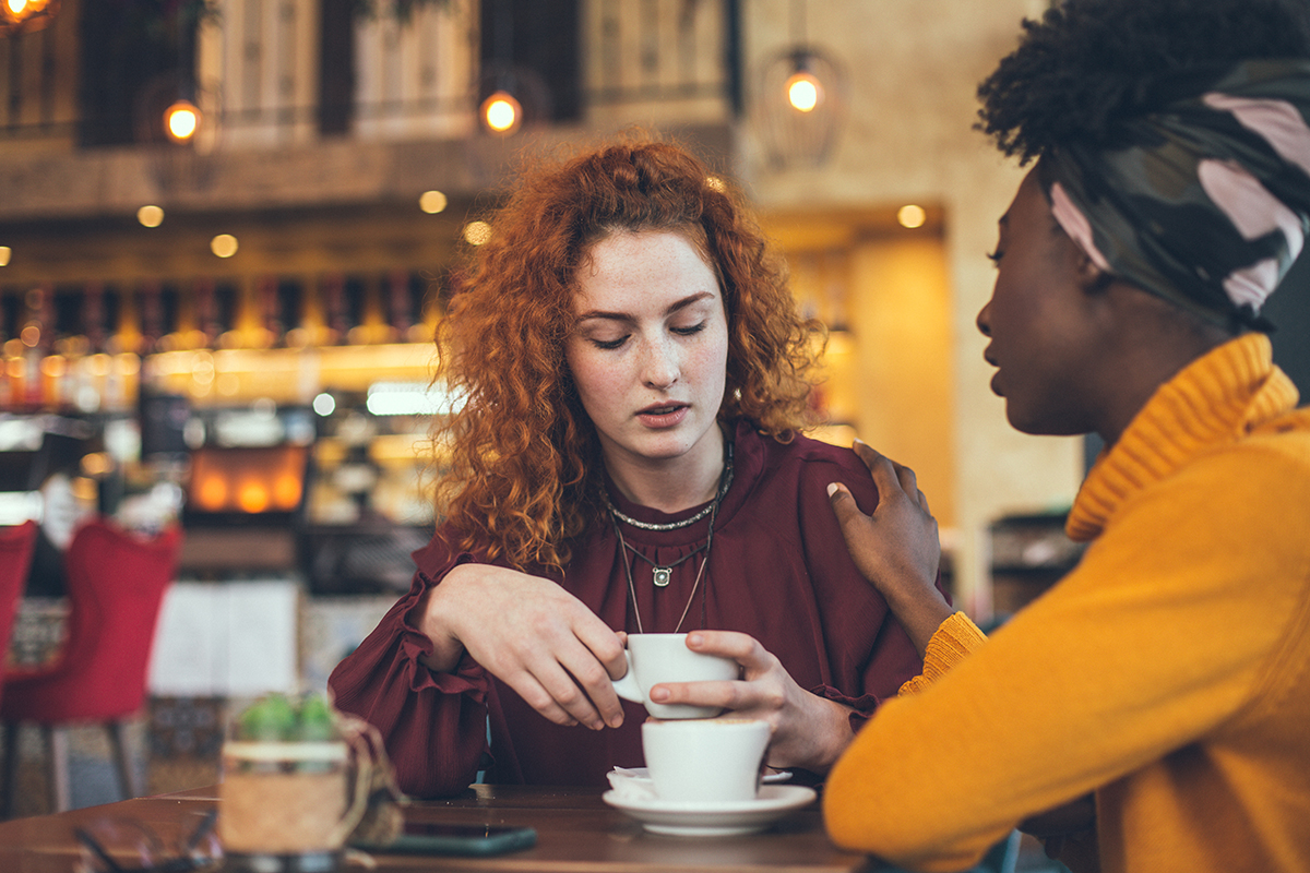 two women talking over coffee about serious topic